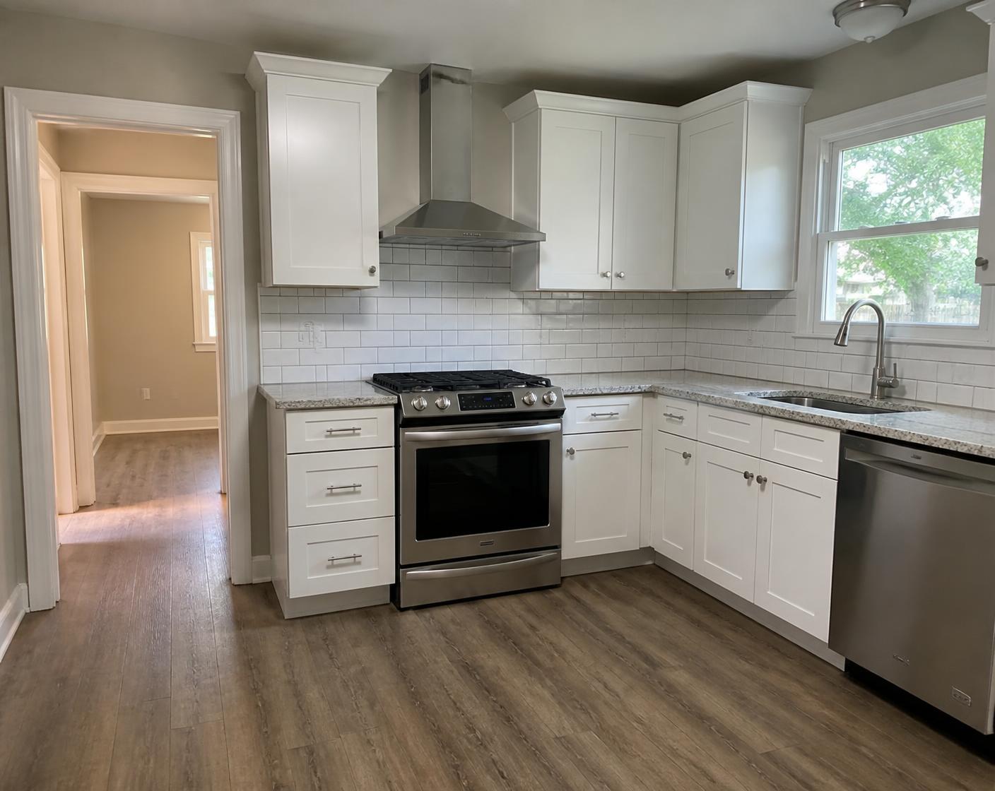 Same kitchen after remodel with white shaker cabinets, granite and new appliances